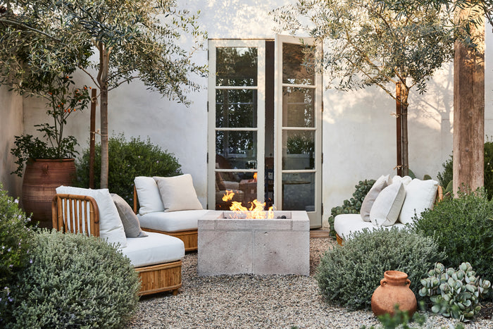 Outdoor patio with fire pit, chairs, and plants in a garden setting.