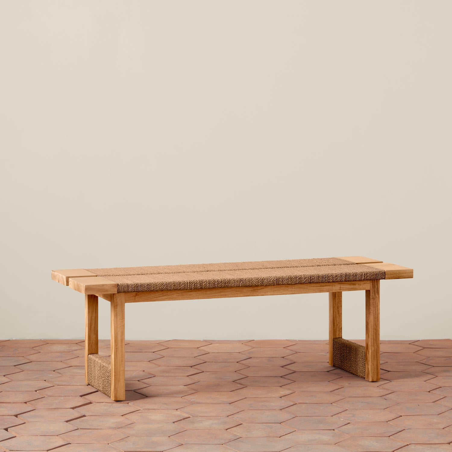 Wooden bench with woven seat on a wooden floor against a beige wall- Number 1