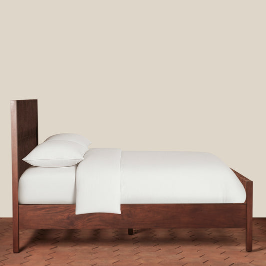 Wooden bed with white bedding against a beige wall - Image 2
