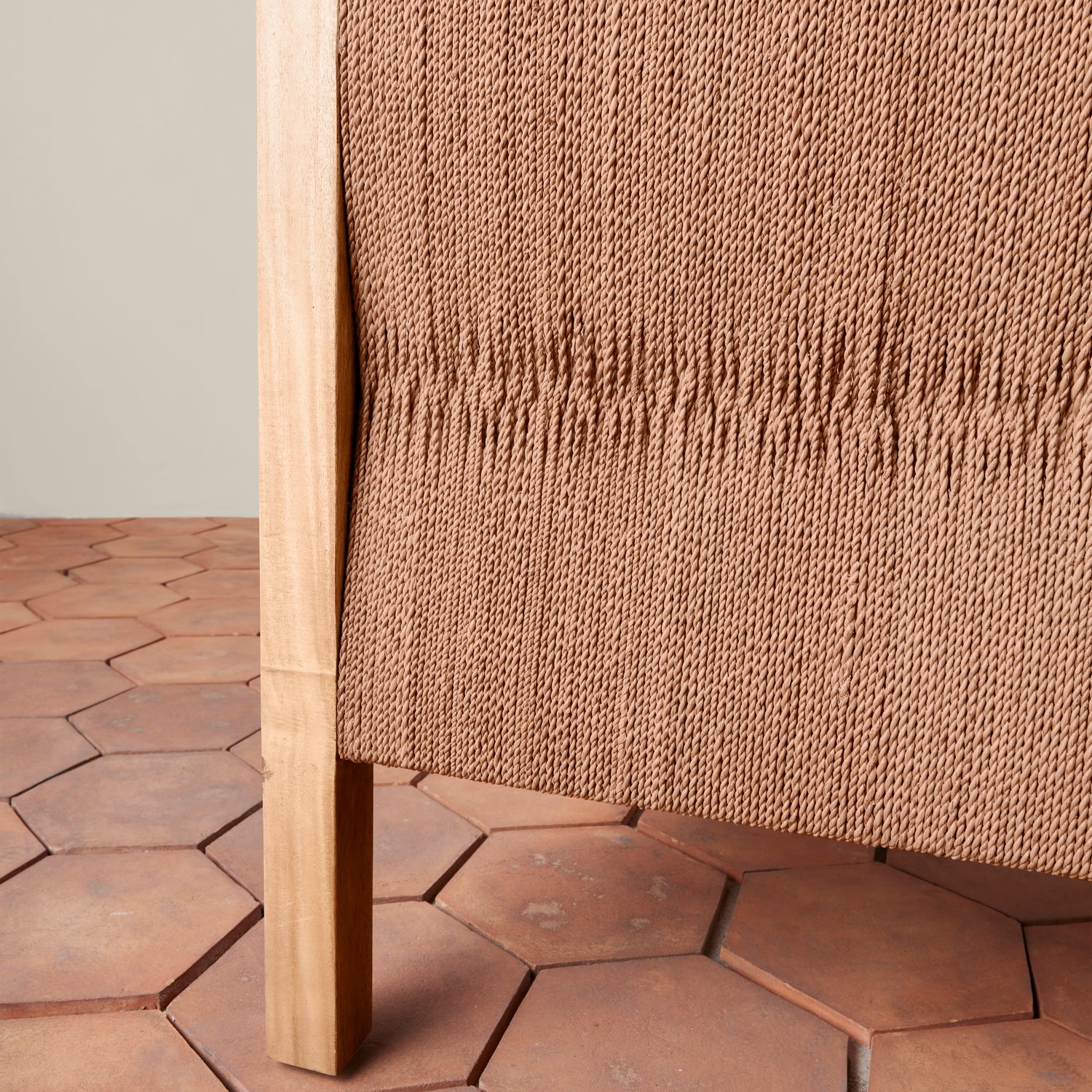 Hexagonal terracotta tiles with a textured brown wall in the background- Number 5