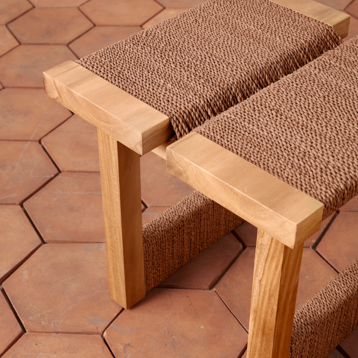 Wooden stool with textured brown seats on a hexagonal tile floor.- Number 7