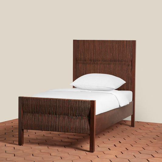 Wooden bed frame with white bedding on a neutral background