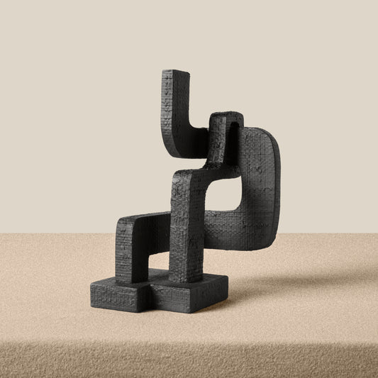 Black abstract sculpture on a beige surface with a beige background