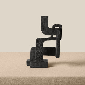 Black textured sculpture on a beige surface with a neutral background - Number 3