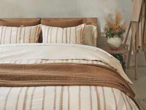 Neatly made bed with striped bedding and pillows in a bedroom setting. - Number 3
