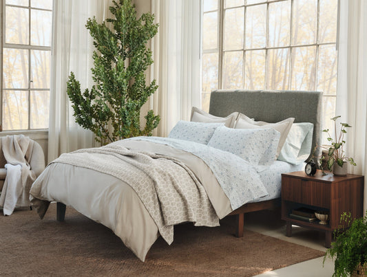 Neatly made bed with light-colored bedding in a bright bedroom with large windows. - Image 2