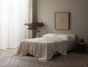 Neatly made bed in a bedroom with a plant and framed artwork on the wall. - Number 3